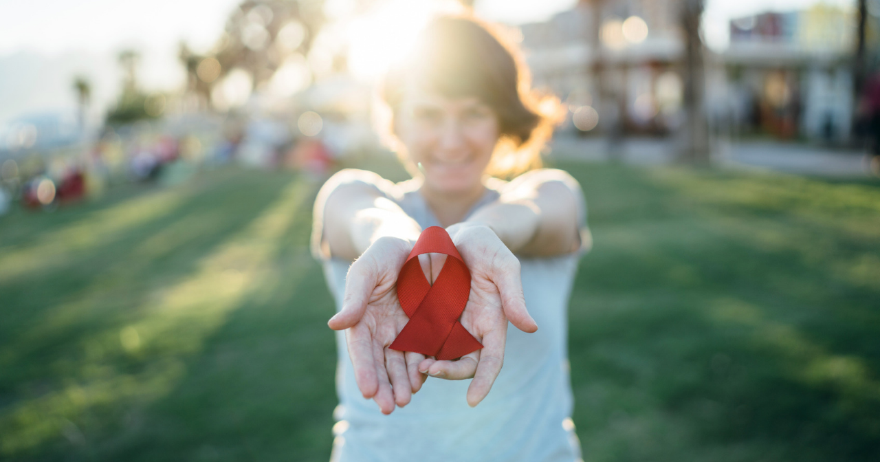 A young woman holding out an AIDS ribbon