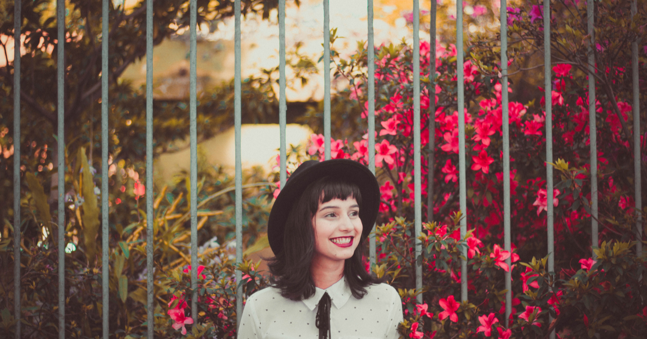 A smiling woman stands in front of flowers