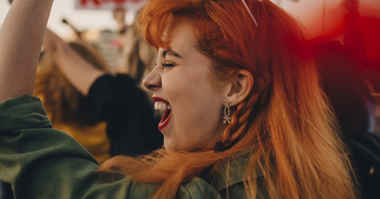 A woman at a protest raises a hand and yells. 