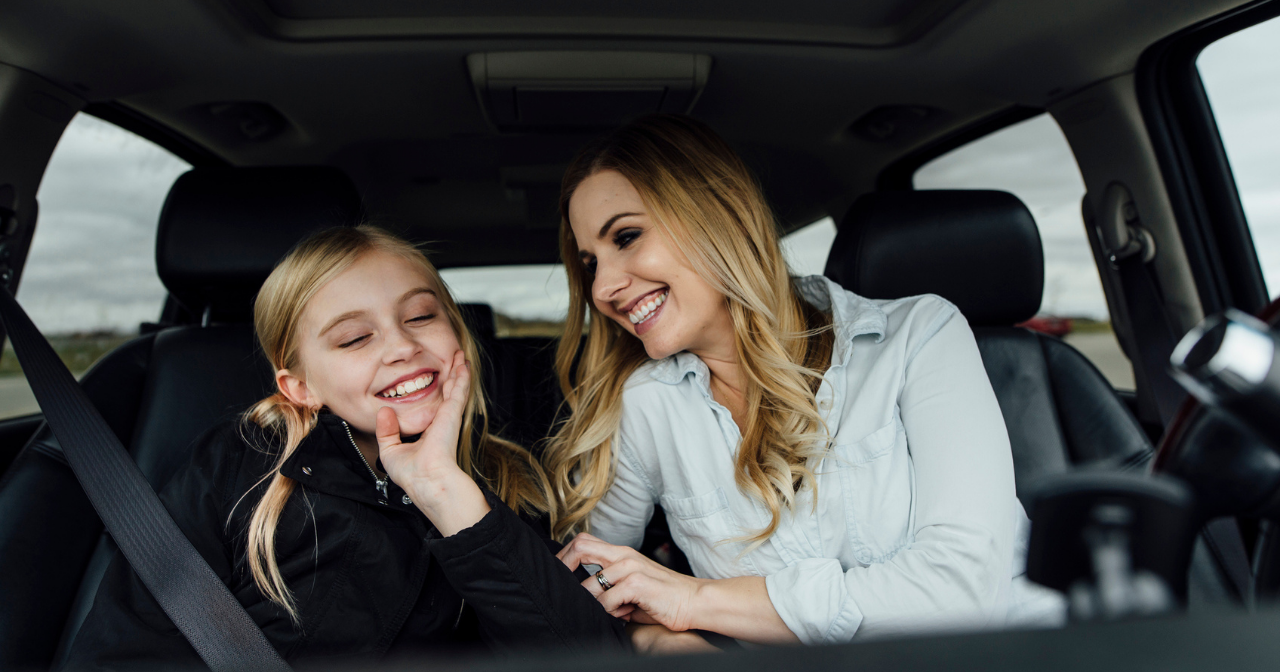 A mom and her middle school age daughter chat in the car together. 