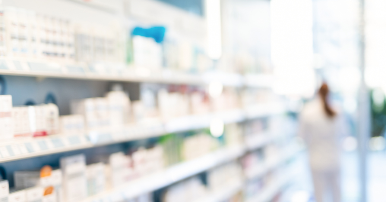 A blurry photo of a bright pharmacy shelf with lots of boxes lined up for sale.
