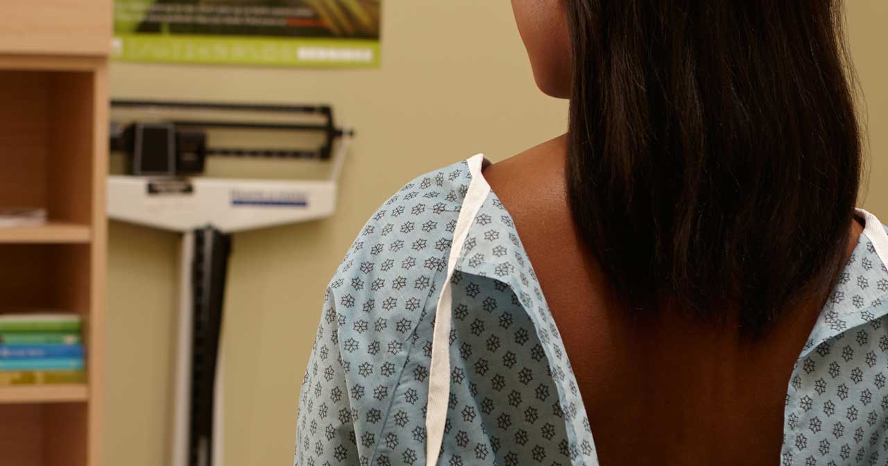 Woman in hospital gown with her back to the camera