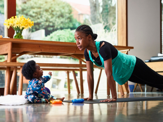 A black woman does yoga with her son watching
