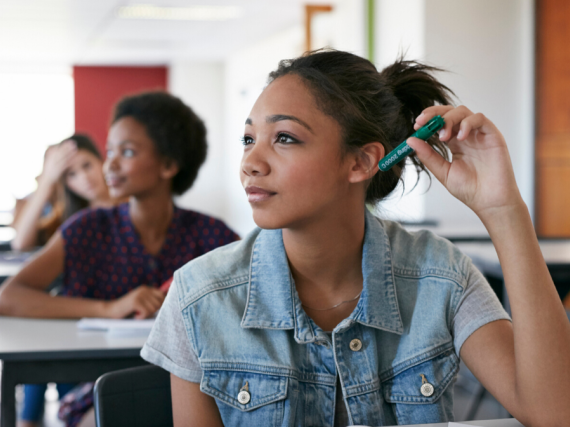 A teenage girl sits at a desk in a classroom and learns. 