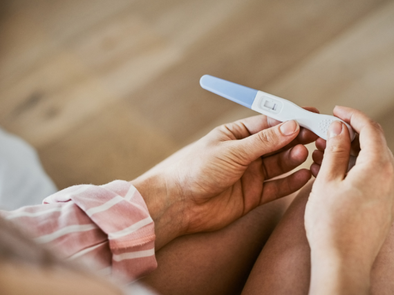 A pair of hands hold a pregnancy test. 