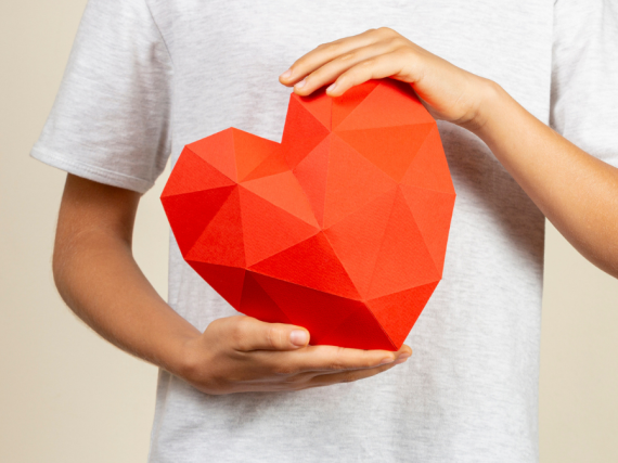 A photo of hands holding a large origami heart. 