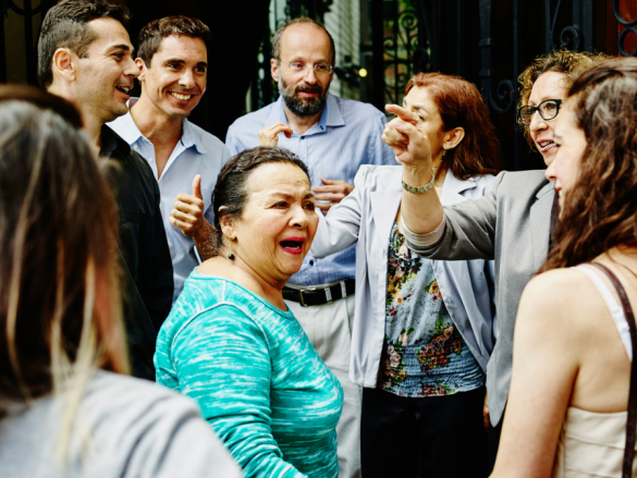 A large multi-generational group of people greet one another. 